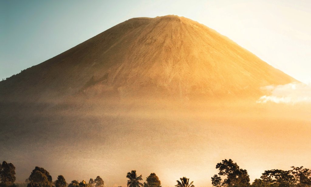 Pemandangan Gunung Semeru dari bawah dengan terpaan cahaya matahari berwarna jingga